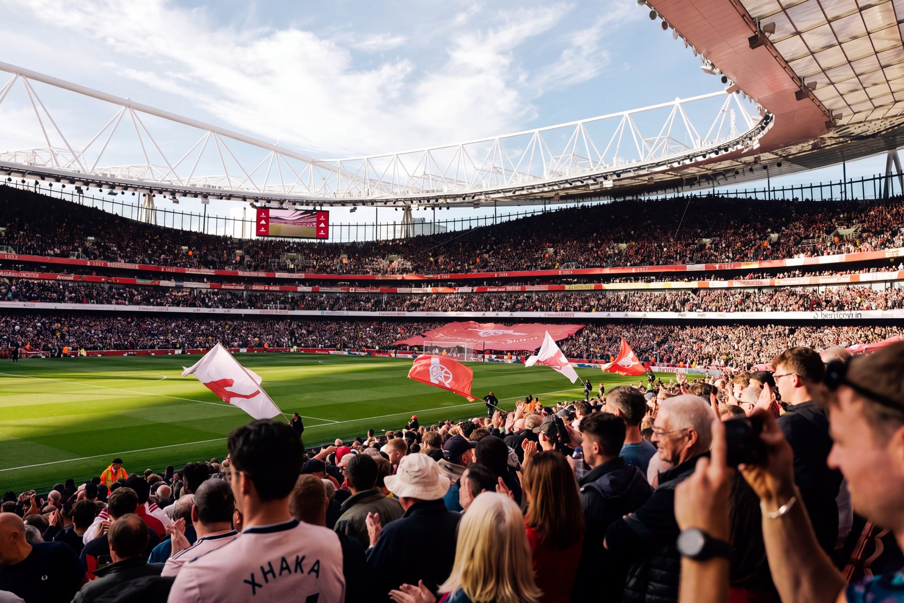 Fans mit Fahnen im vollen Fussballstadion bei Tageslicht